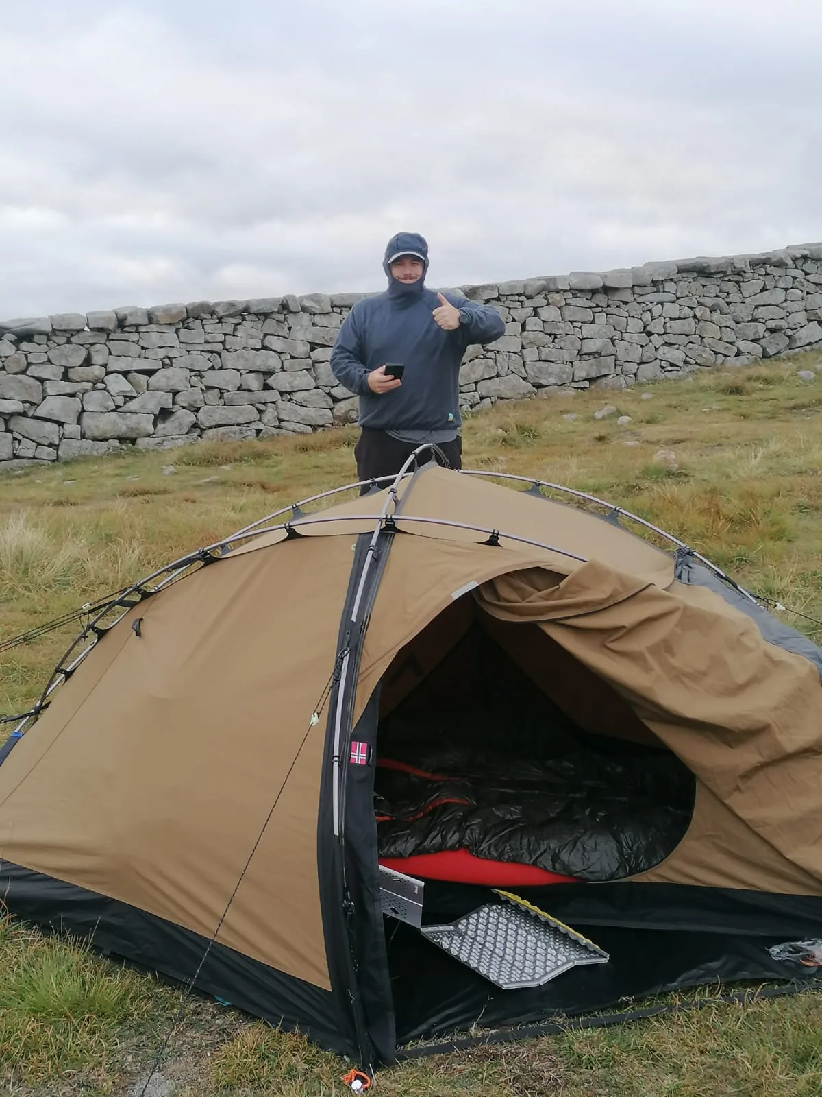 Danny at his wild camp pitch beside the Mourne Wall, thumbs up next to the Nortent Vern 1 PC tent at Lough Shannagh